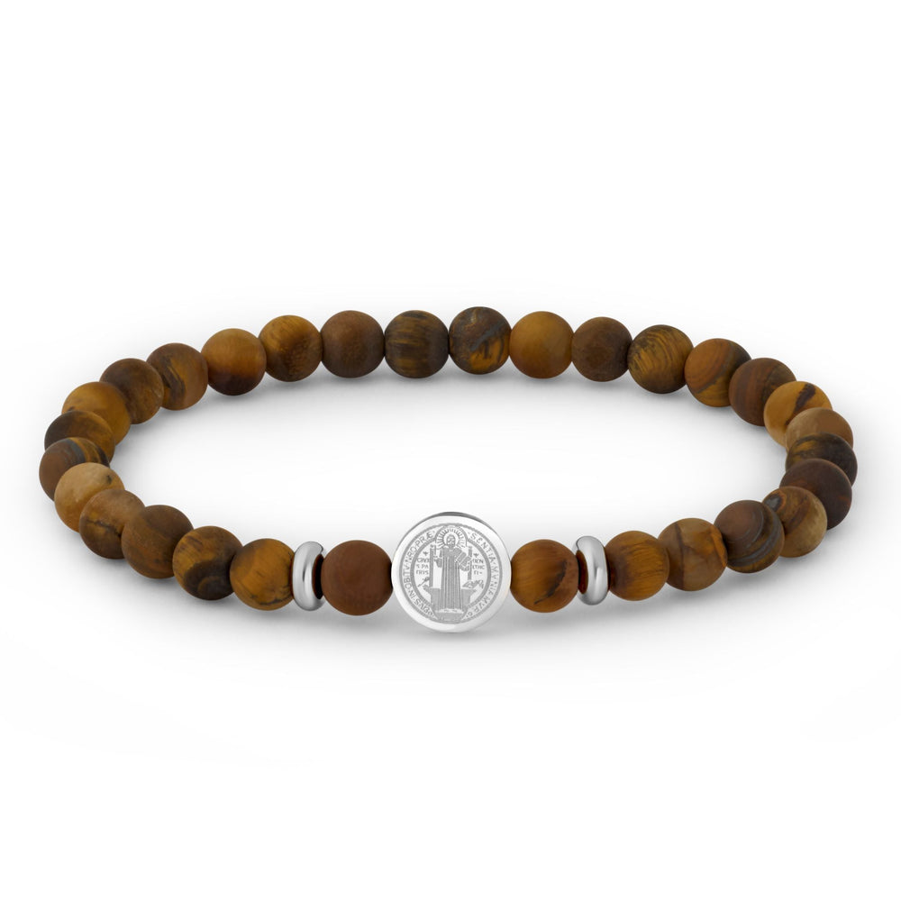 A beaded stretch bracelet made of round brown tiger's eye beads, accented by two small silver spacer beads and a central round silver charm featuring an engraved religious figure.